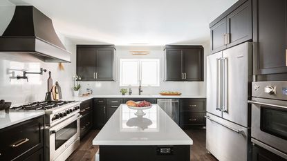 Modern kitchen color ideas are so smart. Here is a black and white kitchen with black cabinets, a silver fridge and oven, white walls, a white kitchen island, and a large window