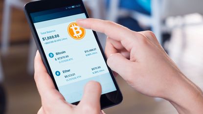 hands holding smartphone. screen has bitcoin position up. 