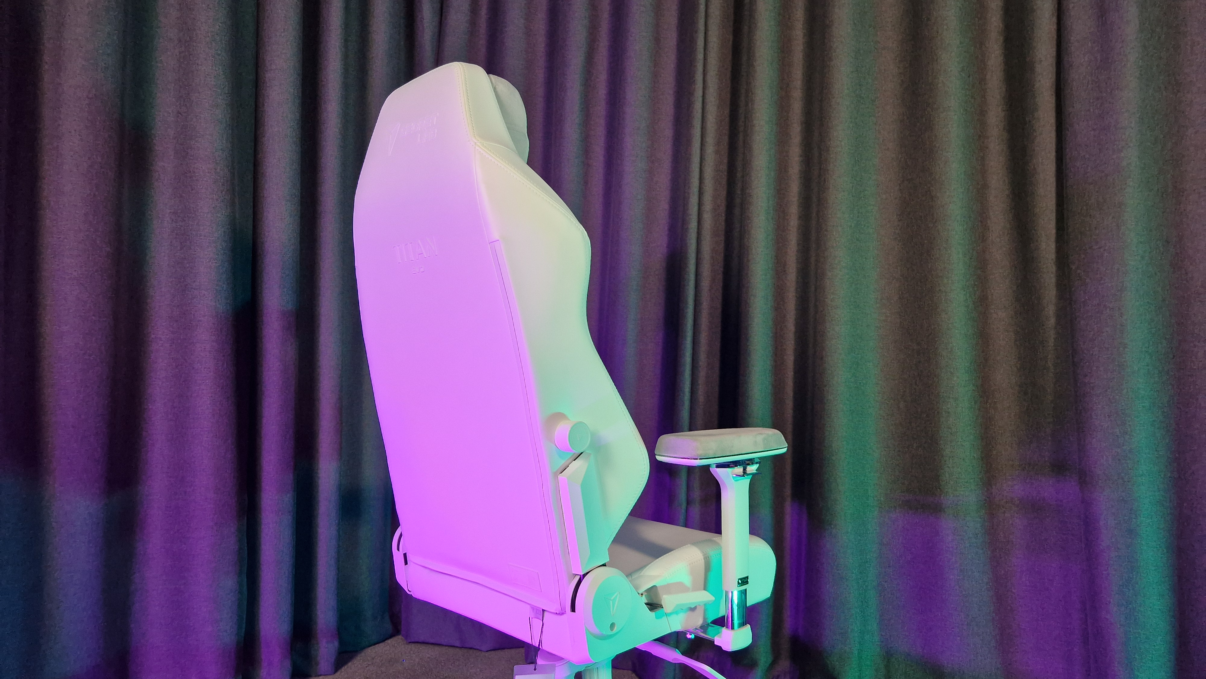 The Secretlab Titan Evo NanoGen Edition chair on a grey floor with grey curtains behind it