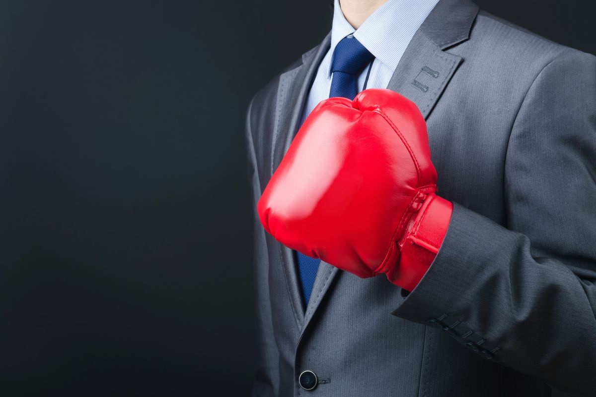 A person in a suit wearing a bright red boxing glove