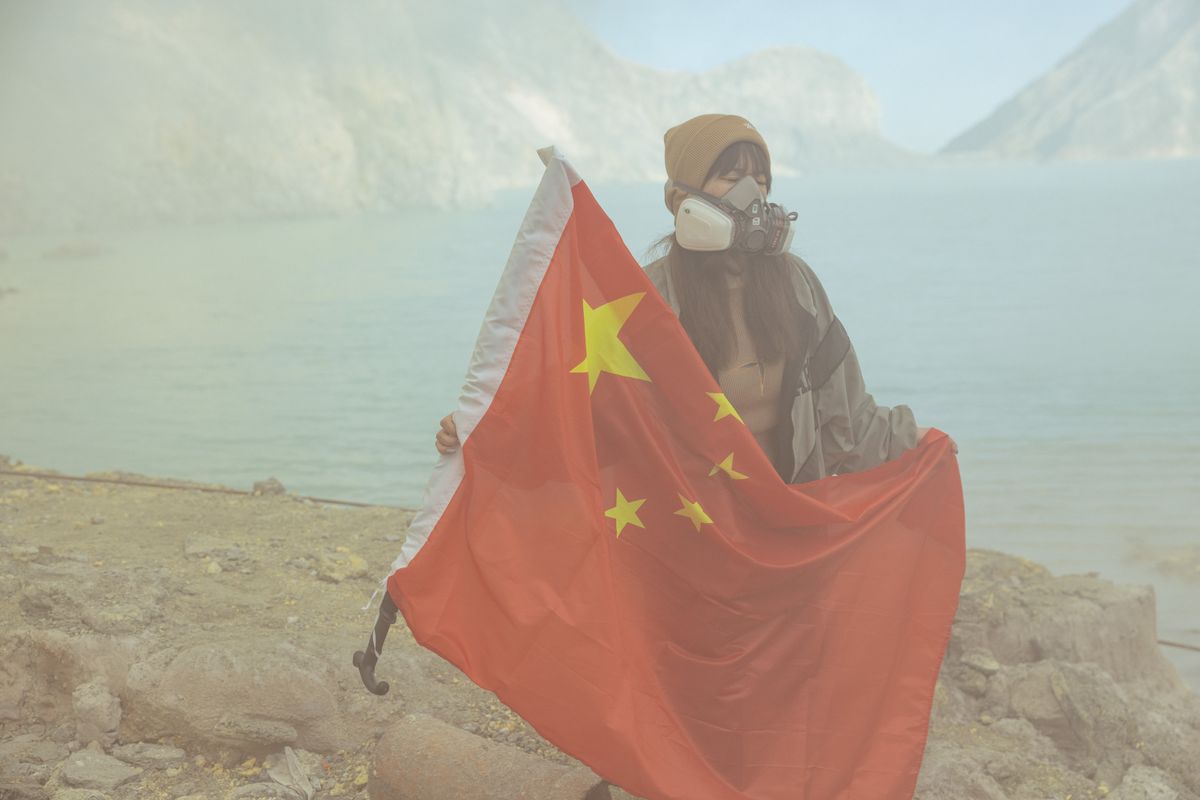 Woman in China holding a Chinese flag and wearing a gas mask in smog 