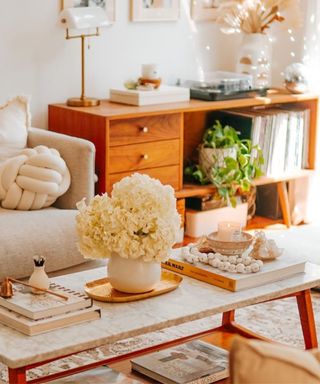 A small living room with a coffee table with decor on, a wooden console table, and a couch