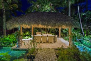 tropical garden ideas with outdoor dining area covered in thatched palm roof