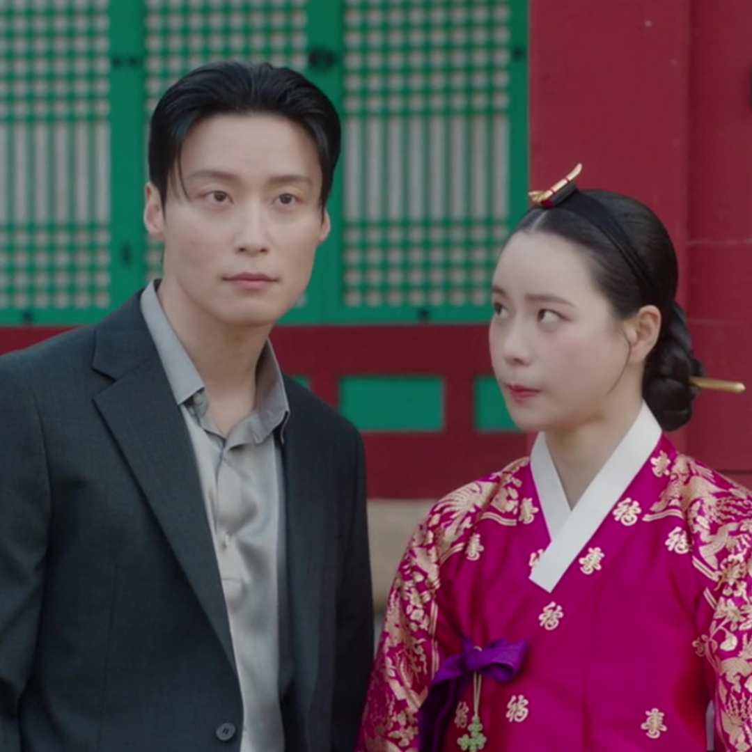 A Korean man in a suit (Heo Nam-jun as Cha Se-gye) and a Korean woman in traditional clothing (Lim Ji-yeon as Shin Seo-ri) stand in front of a traditional palace in 'My Royal Nemesis'.