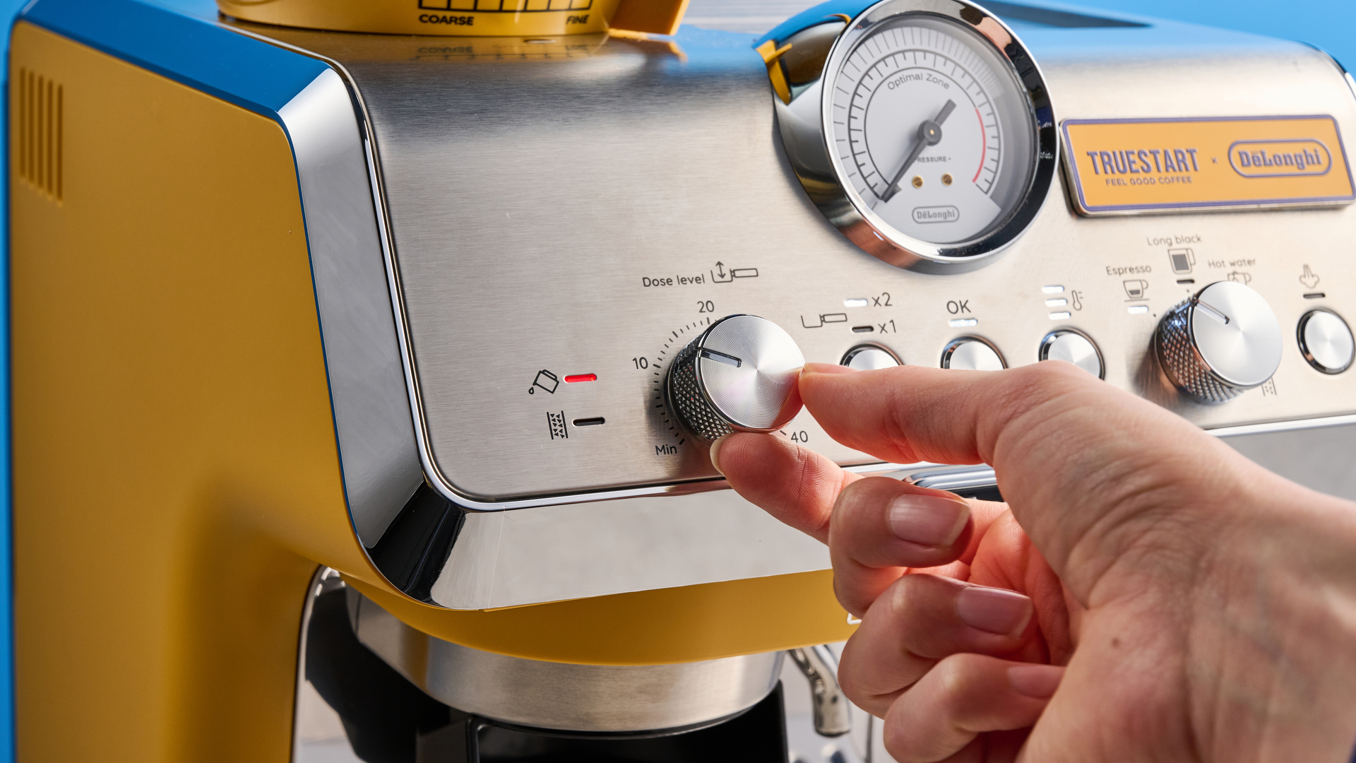 the de&#039;longhi la specialista arte evo special edition truestart edition, with yellow body, showing the espresso machine attachments like tamper, tamping collar, grinder, and control buttons