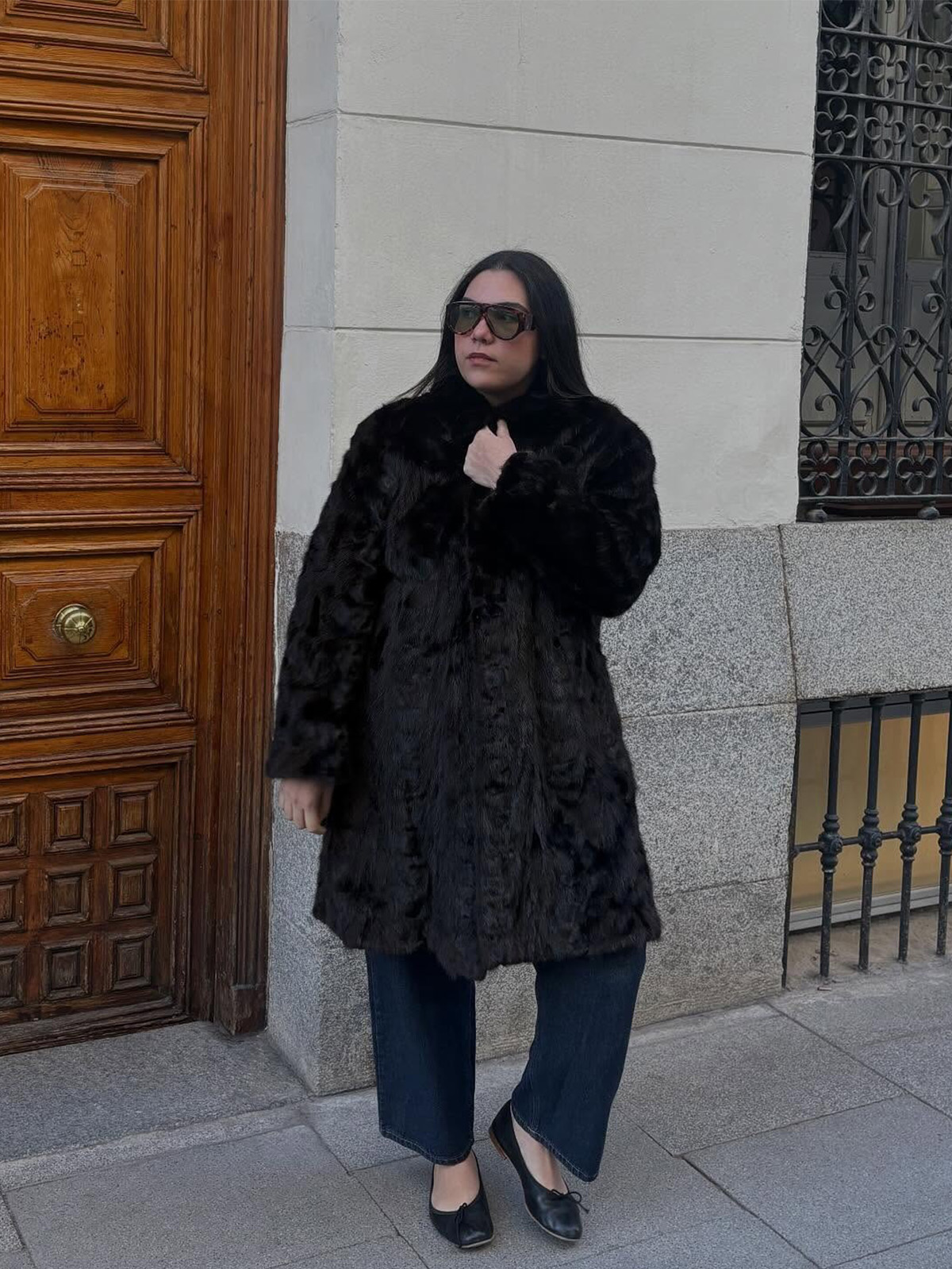Ana Escalante wearing a fur coat, dark-wash jeans, and black flats.