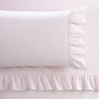 A light pink and white striped ruffle sheet set with a ruffled pillow on top