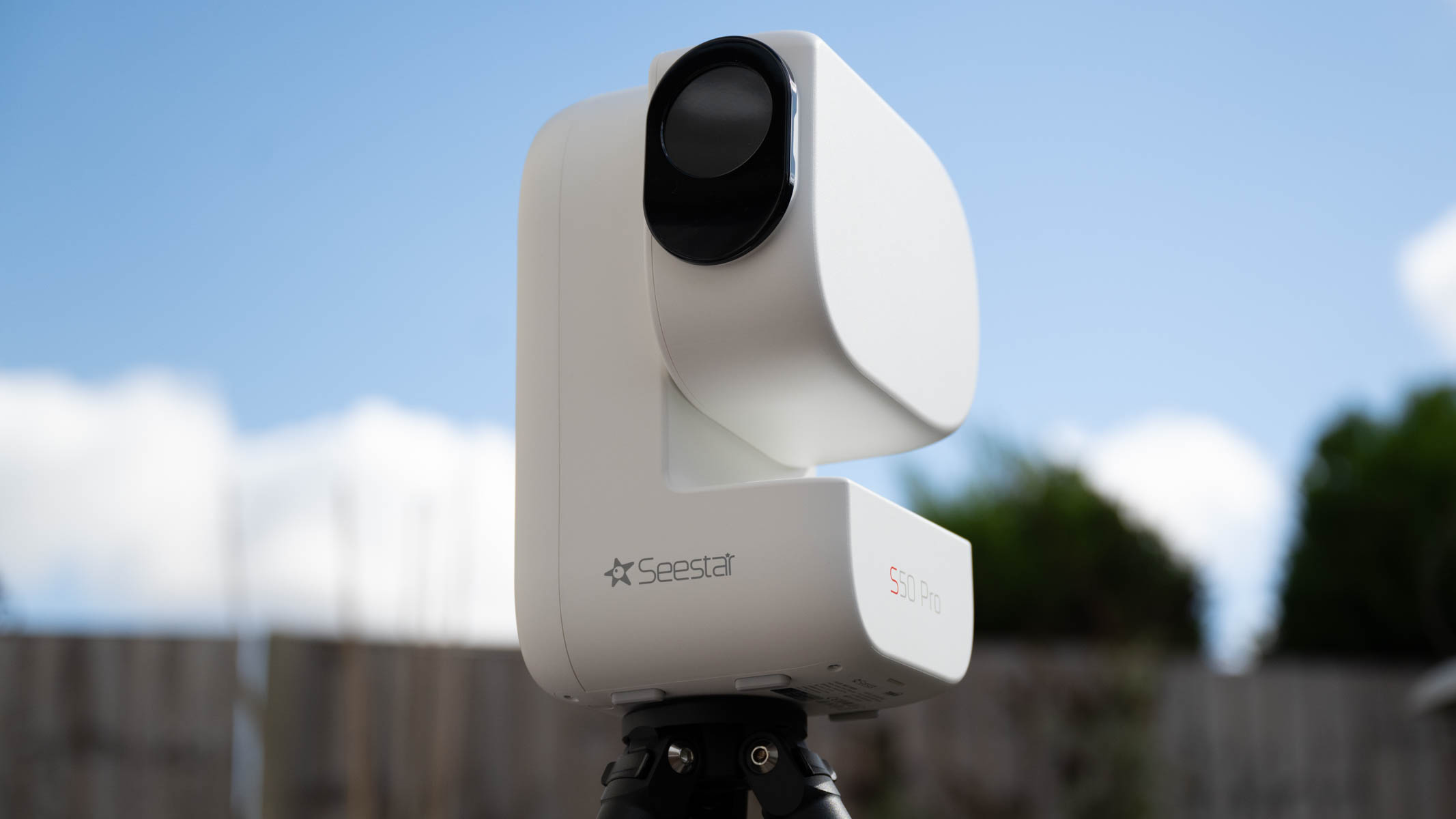 ZWO Seestar S50 Pro on a tripod against a green shed