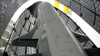 a winged space plane stands up inside its protective fairing before being sealed up for launch