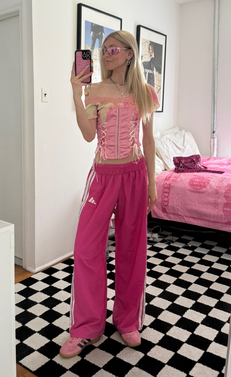 Jessica Minkoff posing in mirror wearing pink corset, pink track pants, and pink adidas sneakers 