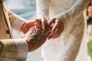 Wedding diet: a close up shot of a woman putting a ring on a mans finger