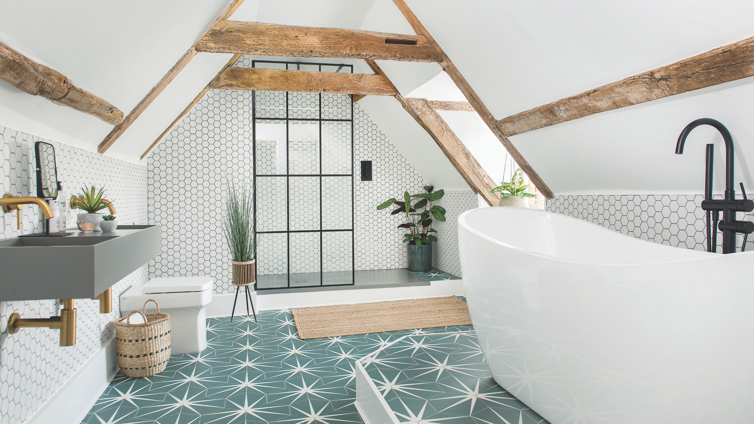 white loft bedroom with exposed wooden beams, green patterned floor tiles, and a freestanding bath with separate shower