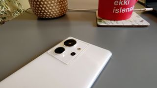 A white-backed Infinix Zero Ultra sitting on a table in front of a red coffee mug and a pot plant