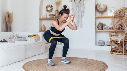 A woman at home performing a banded squat