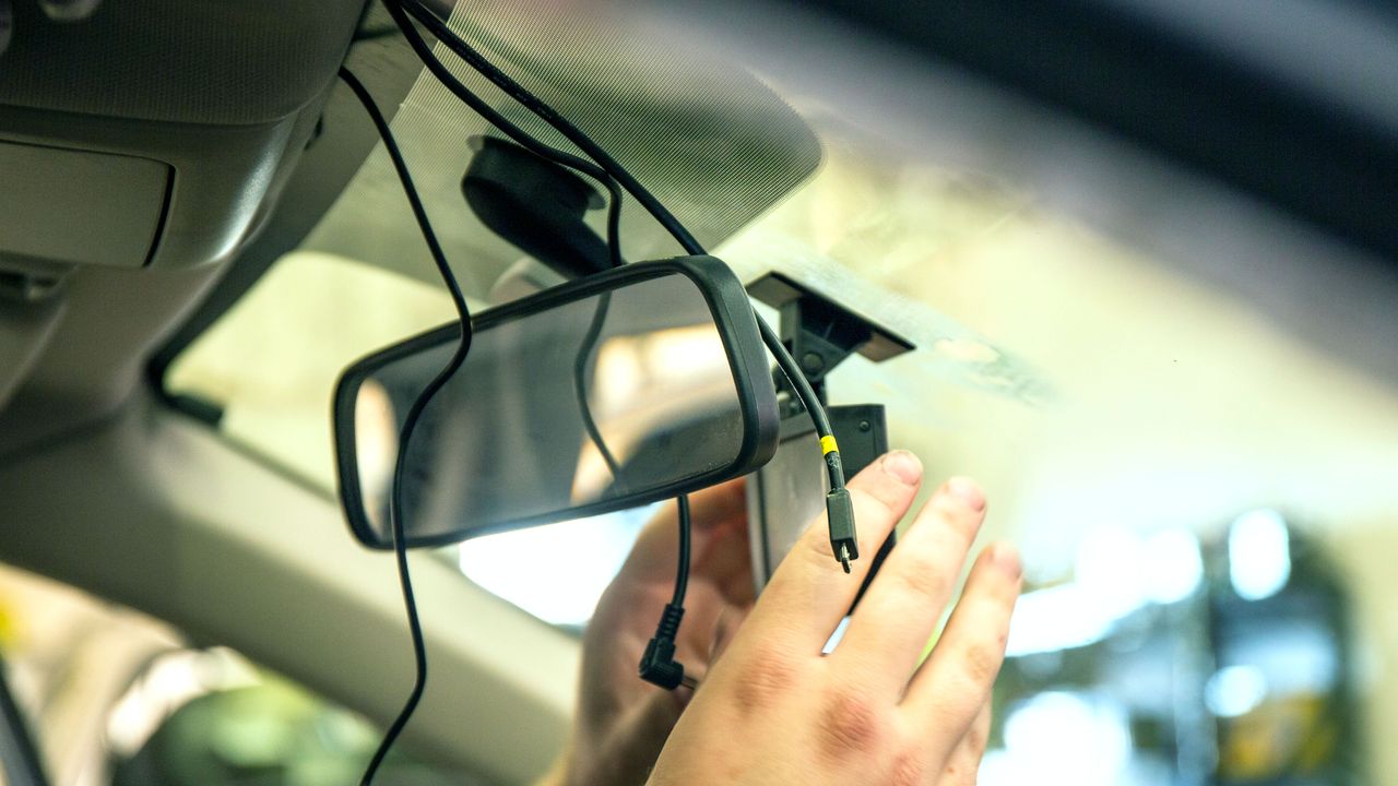 Some hands installing a dash cam into a car's wiring