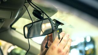 Some hands installing a dash cam into a car's wiring