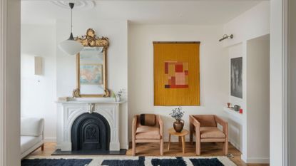 living room with white walls, original fireplace, and mix of antique furniture and art