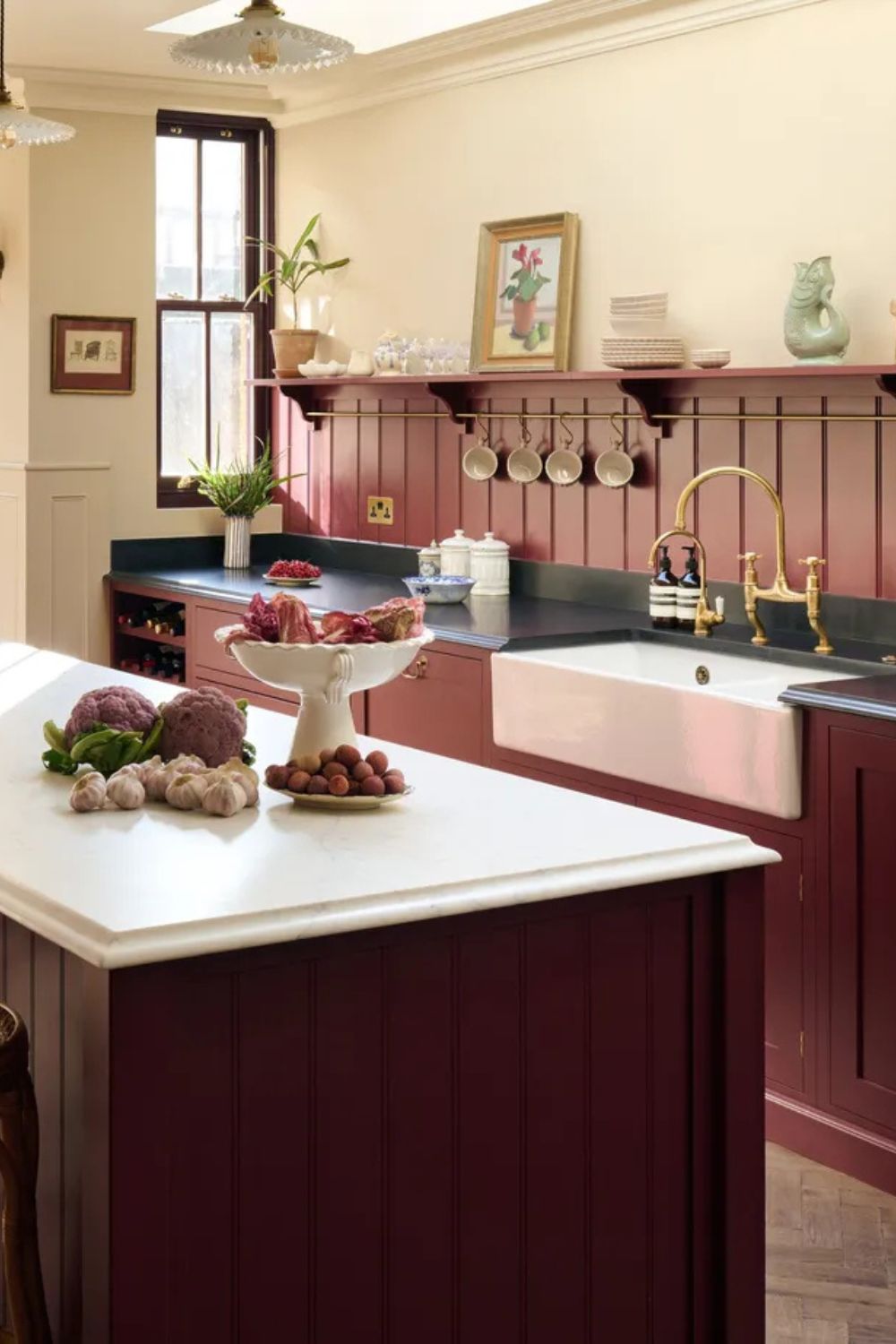 A burgundy kitchen with a paneled backsplash and warm white walls