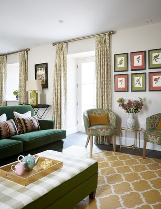 living room with French door curtains, yellow rug, green sofa, artwork on walls armchairs