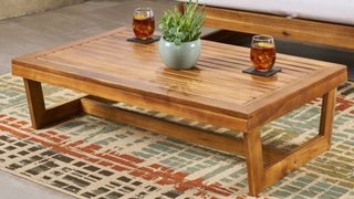 Teak outdoor coffee table on outdoor rug