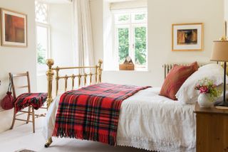 brass bed with white bedlinen and tartan throw