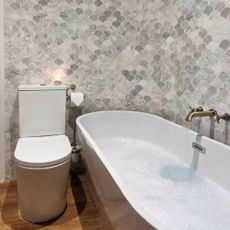 bath tub with toilet and grey wall tiles in bathroom