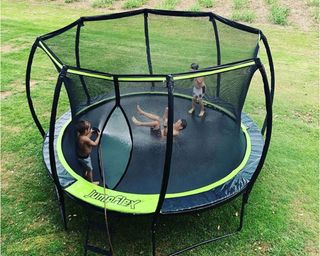 kids playing on a circular trampoline with enclosure