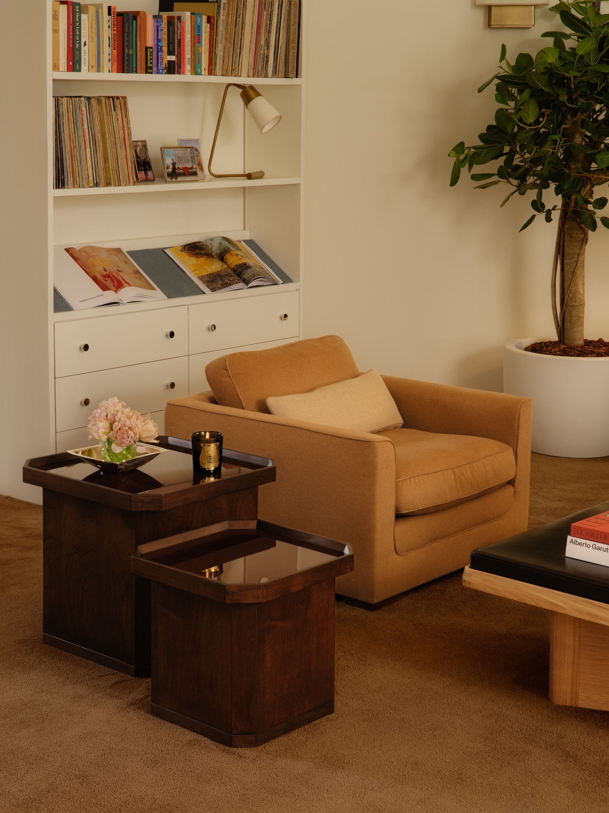 Image of a tan accent chair with two dark wood nesting tables next to it in a white room with teddy bear tan carpeting.