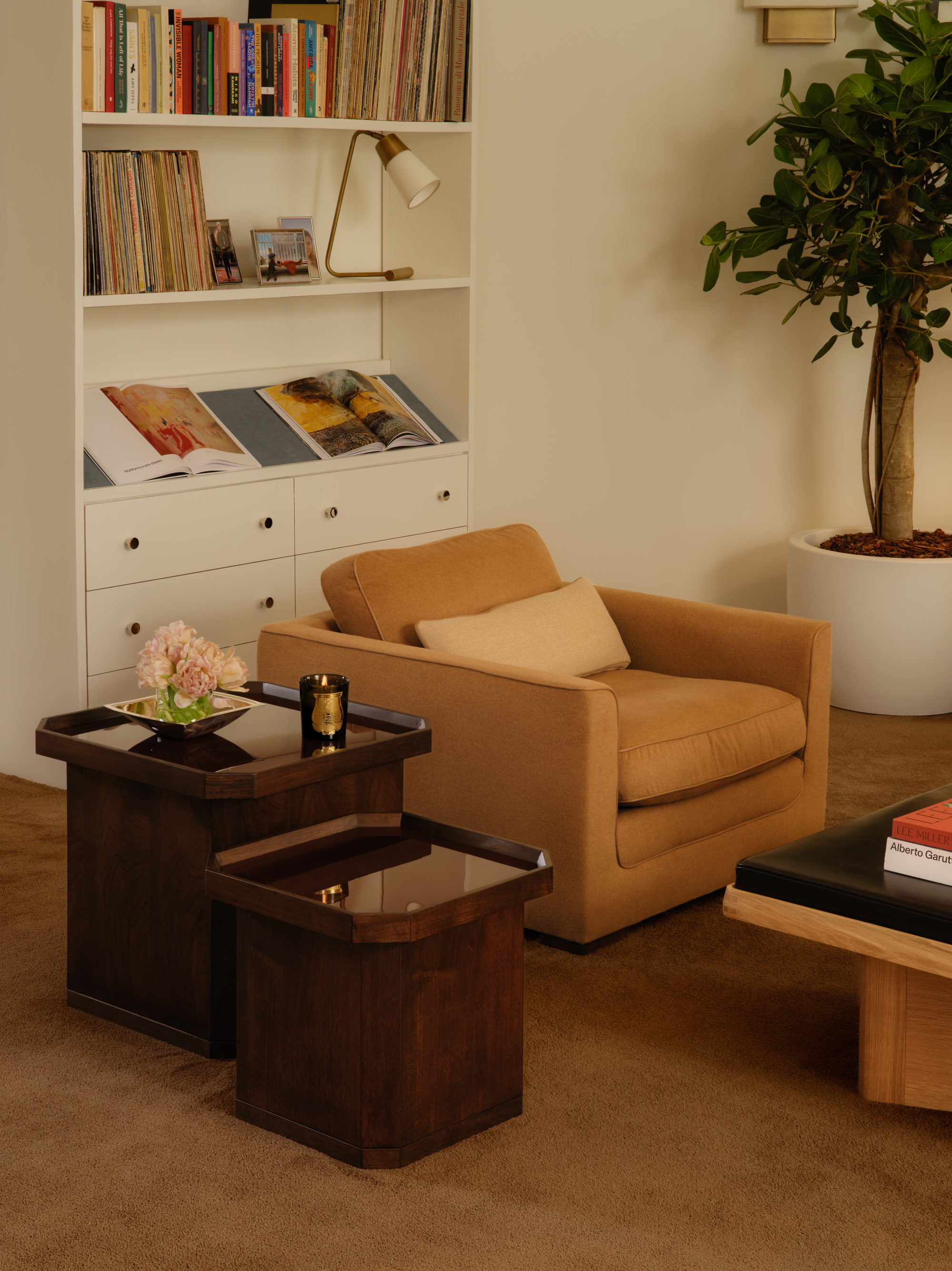 Image of a tan accent chair with two dark wood nesting tables next to it in a white room with teddy bear tan carpeting.