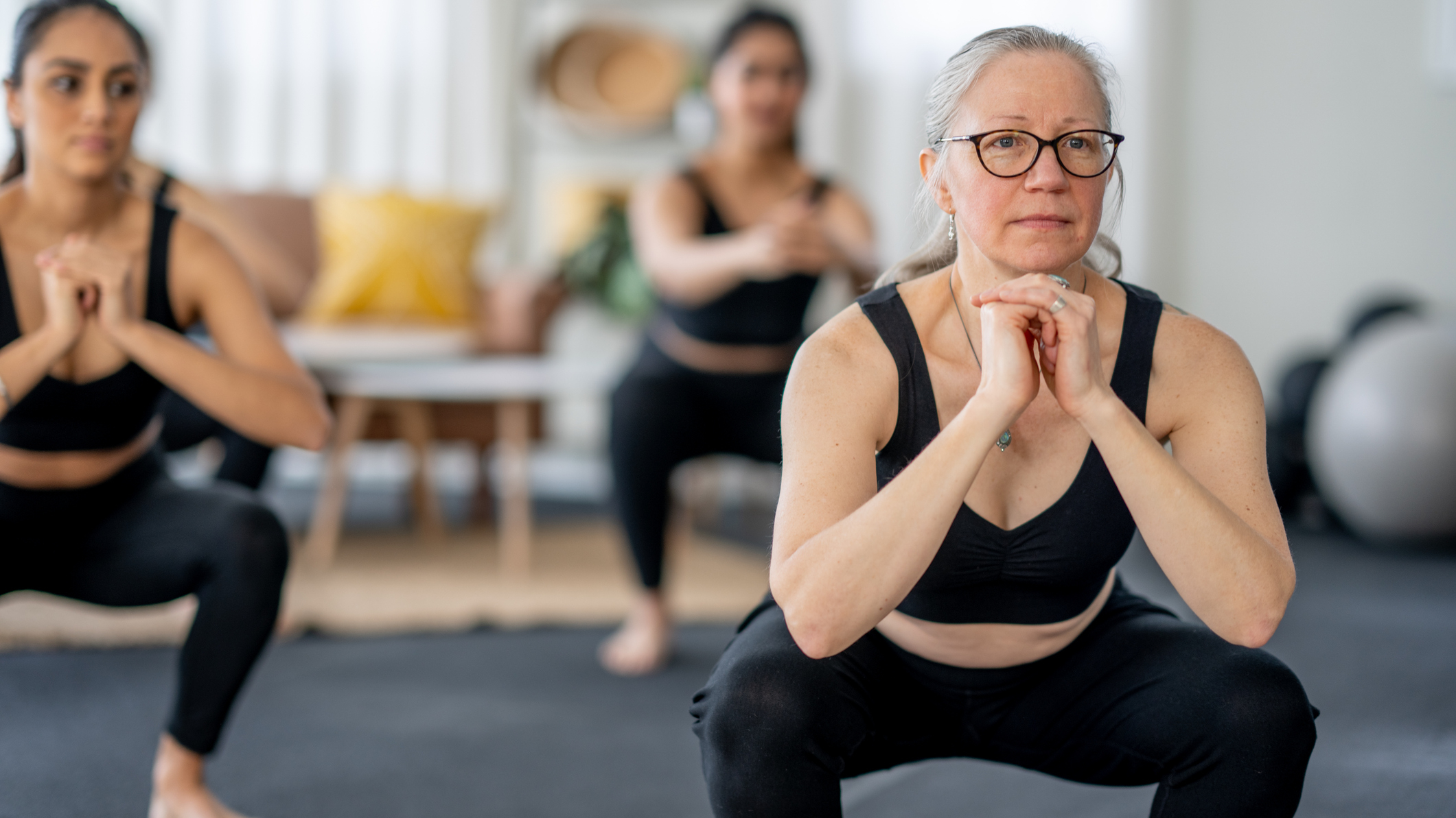 Group of women performing the squat exercise in a domestic setting