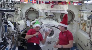 Astronaut David Saint-Jacques of the Canadian Space Agency (left) and NASA astronaut Anne McClain discuss what Christmas in space means to them in a video released Dec. 20, 2018.