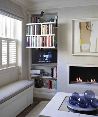 TV mount that hides a TV behind a bookshelf and automatically opens when needed in a neutral living room scheme