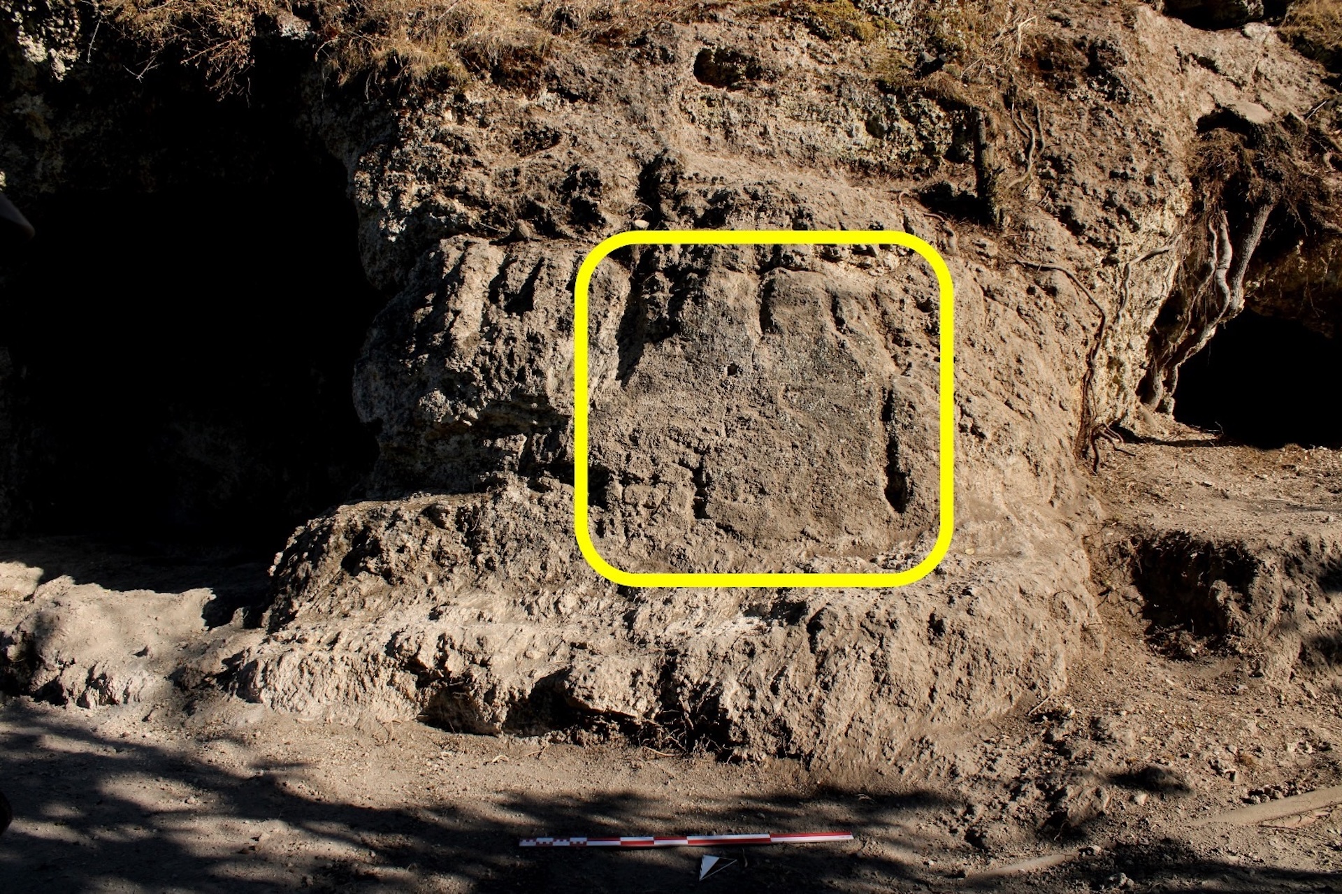 An image with a circled portion showing carved figures in the rock wall