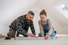 Dad teaching young daughter how bubble level tool works. 