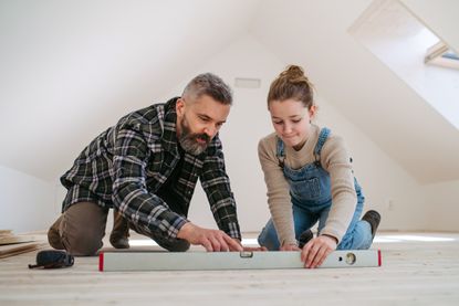 Dad teaching young daughter how bubble level tool works. 