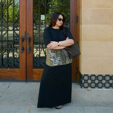 marina wears black dress and sunies while holding a slouchy bag