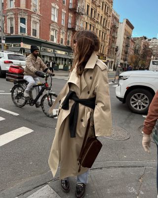 Fashion influencer @jen_wonders in New York City wearing a chic winter outfit featuring the micro-trend of styling your winter coat with a sweater tied at the waist.