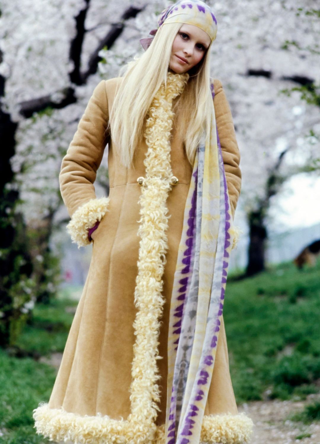 Model Gunilla Lindblad, on a tree-lined path, wearing a white-wool-trimmed shearling long coat by Sawyer Tanning, tie-dyed scarf by Up Tied for Halston. Hair by Christiaan of Henri Bendel.