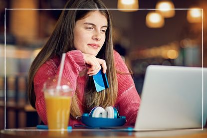 teen girl holding bank card and looking at laptop