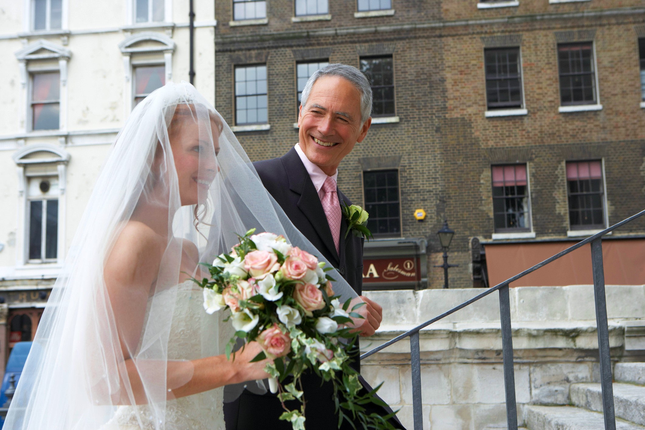 The father of the bride walks his daughter up the church stairs to the wedding.