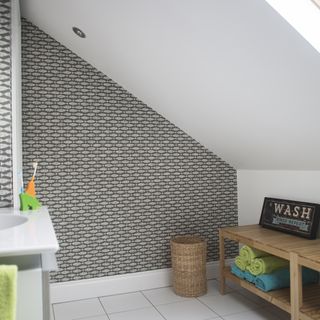 wooden shelving storage in white bathroom black patterned wallpaper white floor tiles sloped ceiling