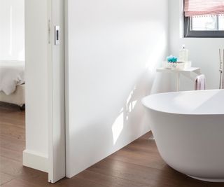 Contemporary white bathroom with dark wooden floors and white ECLISSE sliding pocket door