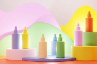A wavy pastel background with skincare bottles without labels. The bottles are also pastel colours of pink, green, yellow, orange and blue.