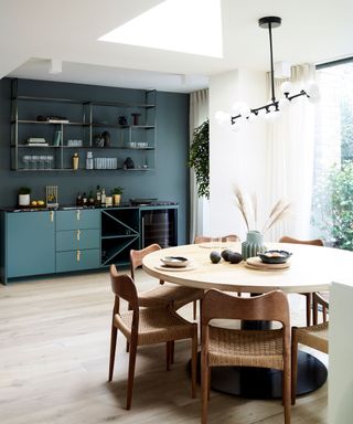 dining area with circular table and chairs with blue cabinetry and large window