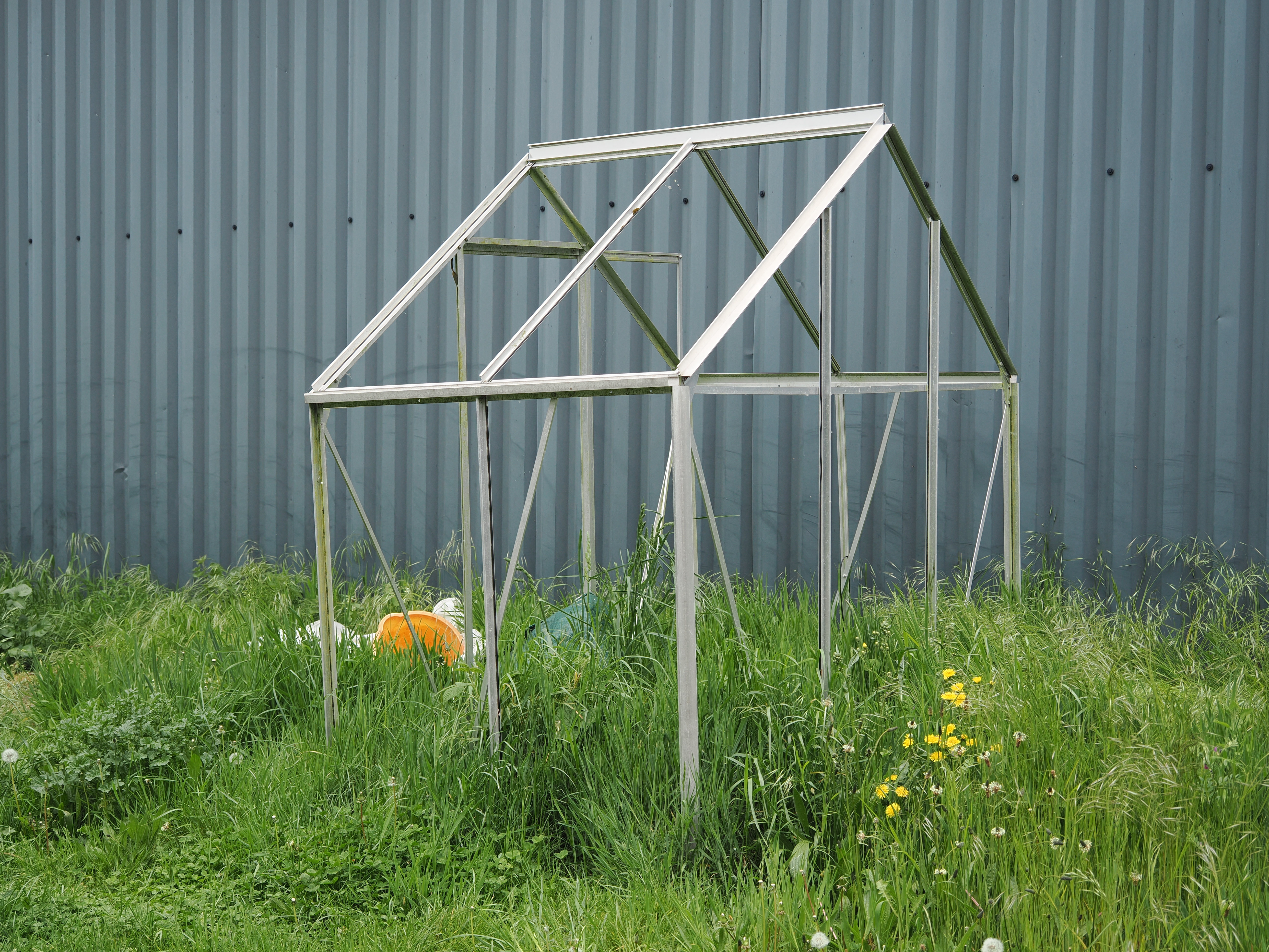 The structure of a small greenhouse standing in a garden