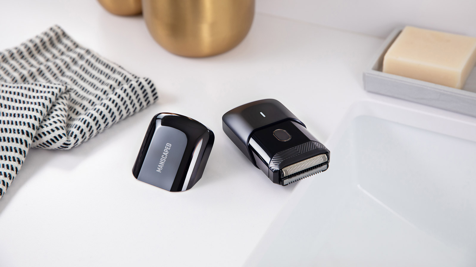 Manscaped Handyman electric shaver resting on edge of sink with magnetic cover taken off