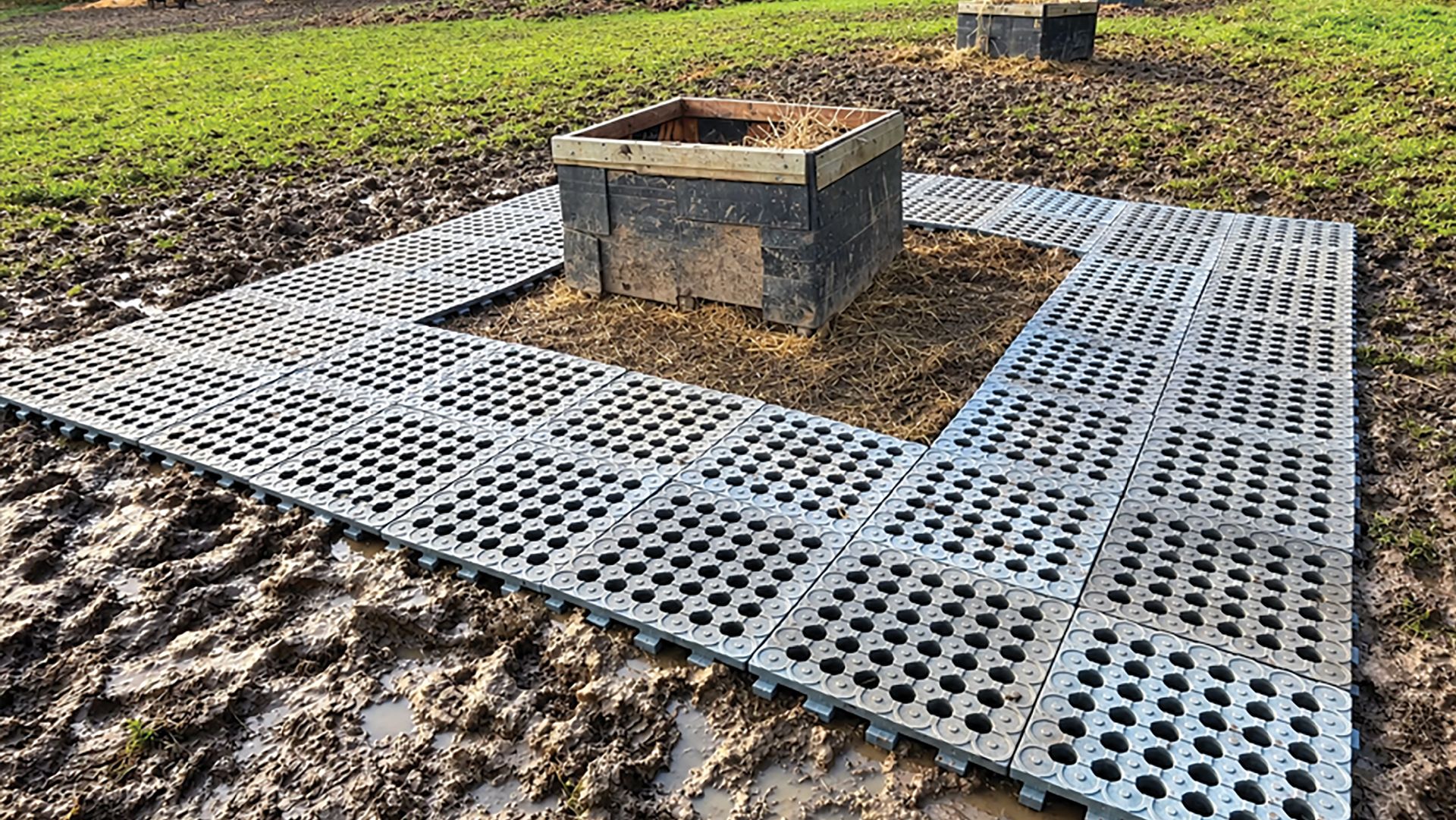 Hay box in muddy field surrounded by mud mats