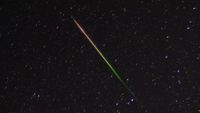 a streak of light crosses through the night sky