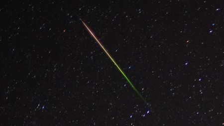 a streak of light crosses through the night sky