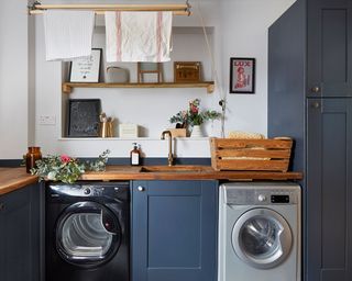 navy blue laundry area with washing machine, dryer, sink and basket